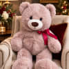 Pink teddy bear with a red ribbon sitting on an armchair