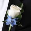 White rose boutonniere with a blue accent flower on a black suit