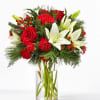 Red roses, white lilies, and carnations in a clear glass vase