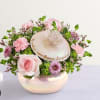 Pink roses and mixed blooms arranged in a round hatbox with a lid
