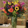 Colorful mixed bouquet in a clear glass vase with lilies and sunflowers