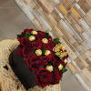 Red roses in a black box with gold chocolates and a crown topper