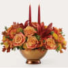 Autumn floral arrangement with roses and candles in a gold bowl
