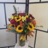 Bouquet of sunflowers, roses, lilies, and gerbera daisies in a glass vase