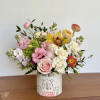 Mixed bouquet of pink, white, and yellow flowers in a decorated ceramic vase