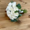 White rose bouquet with green foliage on a wooden surface