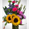 Mixed bouquet with sunflowers, carnations, and lilies in a glass vase