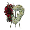 Heart-shaped funeral wreath with red and white flowers on a stand