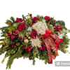Large holiday floral arrangement with red and white flowers and a red ribbon