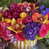 Colorful bouquet in a gold vase with orchids, roses, hydrangeas, and ranunculus