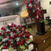 Large red rose funeral spray on a casket with a matching standing spray