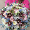 Pastel bouquet with orchids, ranunculus, and blue berry-like accents