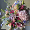 Mixed bouquet with pink roses, lilies, and hydrangea in paper wrap