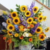 Large mixed bouquet with sunflowers, purple spikes, and a patterned ceramic vase