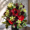 Red anthuriums and green orchids in a black vase
