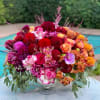 Colorful bouquet of roses, dahlias, and orchids in a silver vase