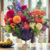 Colorful mixed flower arrangement in a silver pedestal vase