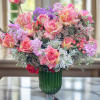 Pink and peach roses arranged in a green glass vase