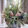 Large mixed floral arrangement in a decorative vase with pink and green blooms