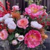 Pink and white floral arrangement with red berry branches in a glass vase