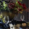 Dark floral centerpiece with red blooms in a gold bowl on a decorated table