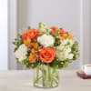Orange roses and white flowers in a clear glass vase