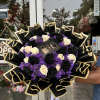 Bouquet of black and cream roses with purple filler and black-gold wrapping