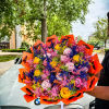 Large bouquet of multicolored roses wrapped in bright orange paper