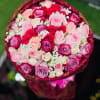 Round bouquet of pink, red, and lavender roses with white filler flowers