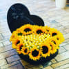 Heart-shaped black box filled with sunflowers and gold chocolates
