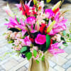 Pink lilies and roses arranged in a burlap-wrapped bouquet