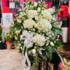 White floral standing spray with a ribbon bow
