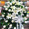 A lush spray of white lilies and roses creates a serene, comforting