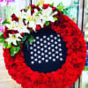 A bold circle of bright red carnations forms the wreath's striking frame
