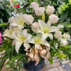 White lilies and pale roses in a dark vase with a satin ribbon
