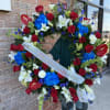 Large floral wreath with red roses, white lilies, and blue hydrangeas