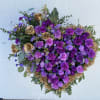 Heart-shaped purple floral spray with gold roses on a stand