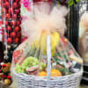 Fruit and snack gift basket in a white wicker basket with tulle wrap