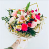Bouquet of pink roses, lilies, and carnations with gold ribbon