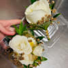 Two small white rose boutonnieres in clear plastic cases