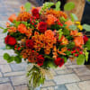 Bouquet of red and orange roses with orange chrysanthemums in a glass vase