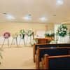 Funeral chapel with white floral wreaths and sprays around a casket
