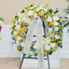 Yellow and white rose wreath on an easel with a memorial ribbon