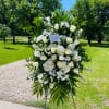 Large white floral standing spray on an easel outdoors