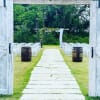 Outdoor wedding aisle with white chairs and a floral arch