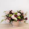 Pink and purple flower arrangement in a blush pedestal vase
