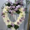 Heart-shaped floral wreath with lavender roses and white blooms on an easel