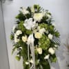 White and green funeral spray with roses and chrysanthemums on a stand