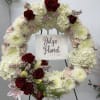 Large floral wreath with white blooms and red roses on an easel