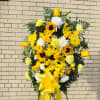Yellow and white floral standing spray with a large ribbon bow